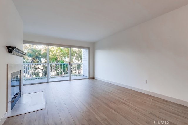 unfurnished living room with wood finished floors, a glass covered fireplace, and baseboards
