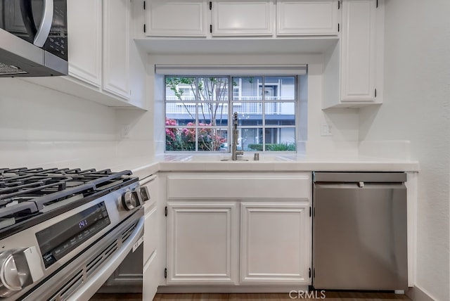 kitchen featuring stainless steel appliances, white cabinets, light countertops, and a sink