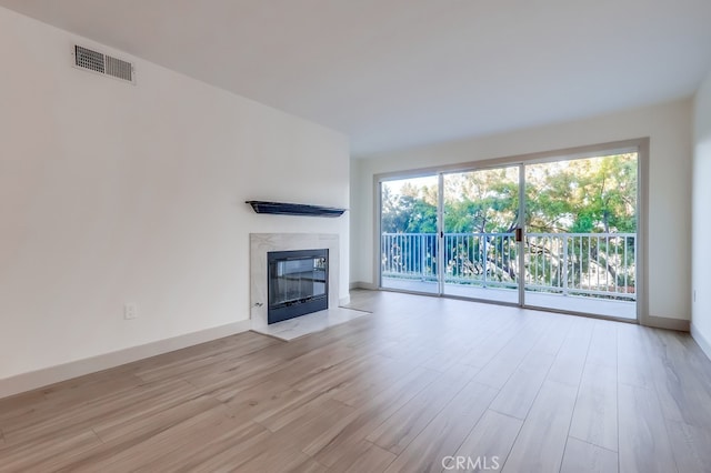 unfurnished living room with wood finished floors, a premium fireplace, and baseboards