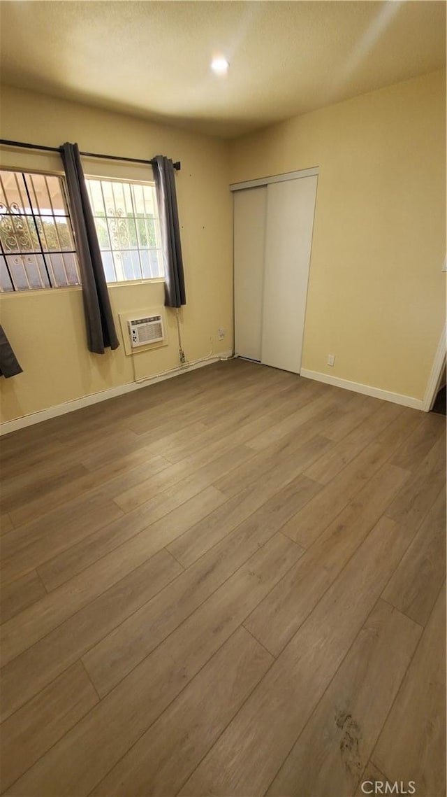 44709 6th St E, Lancaster, CA 93535 - unfurnished bedroom featuring wood finished floors, a wall unit AC, a closet, baseboards, and recessed lighting