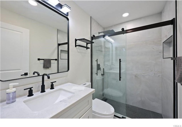 bathroom with toilet, a shower stall, vanity, and recessed lighting