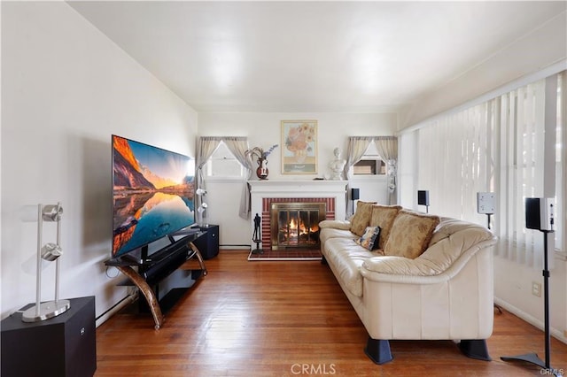 living area with a brick fireplace and wood finished floors