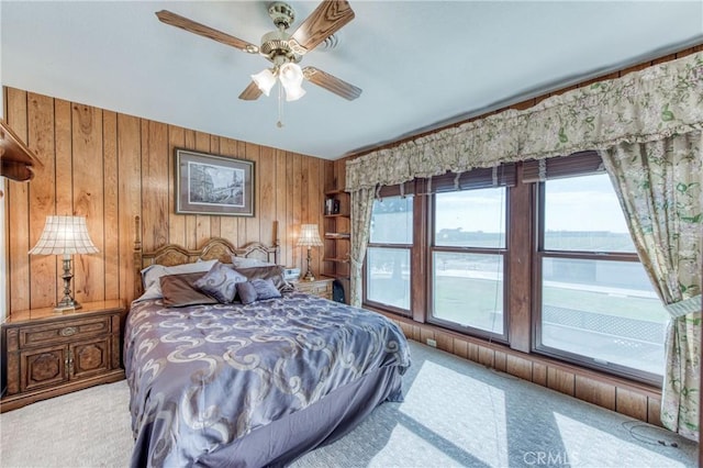carpeted bedroom with wooden walls and a ceiling fan