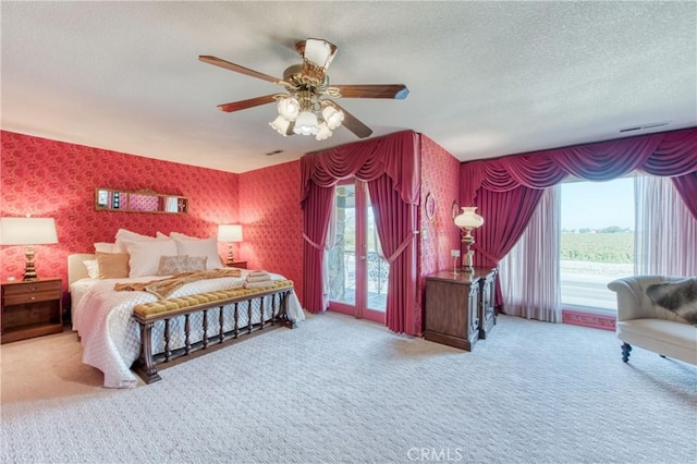 carpeted bedroom featuring wallpapered walls, access to exterior, multiple windows, a textured ceiling, and ceiling fan