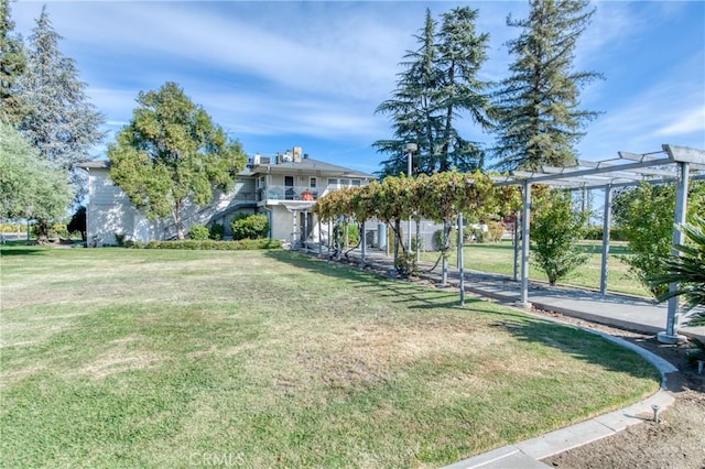 view of green lawn featuring a pergola and a balcony