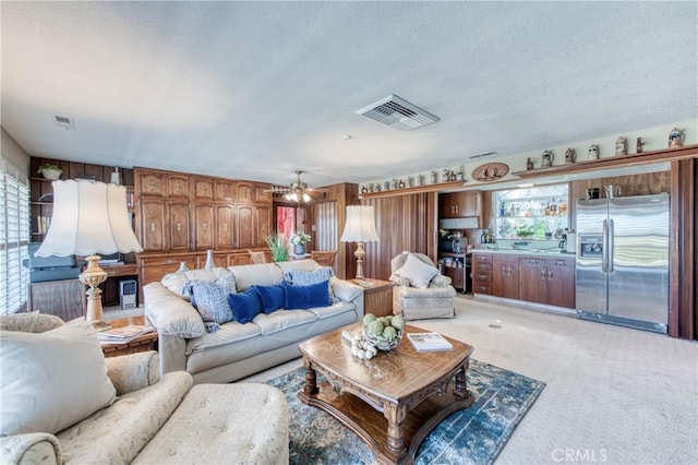 living room with ceiling fan, light colored carpet, and a textured ceiling