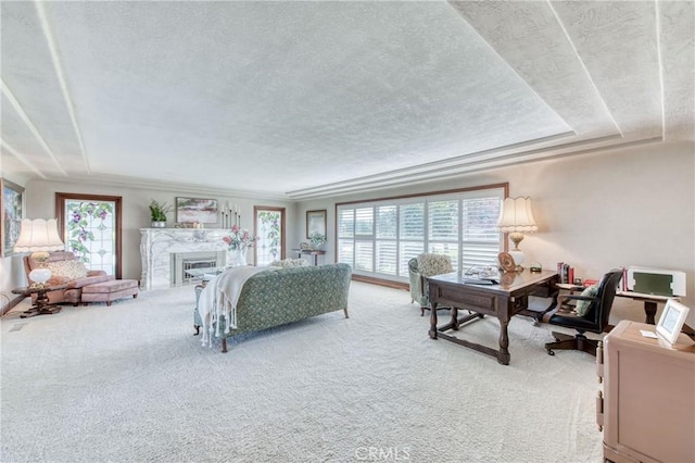 living area featuring a textured ceiling, healthy amount of natural light, carpet floors, a desk, and a fireplace