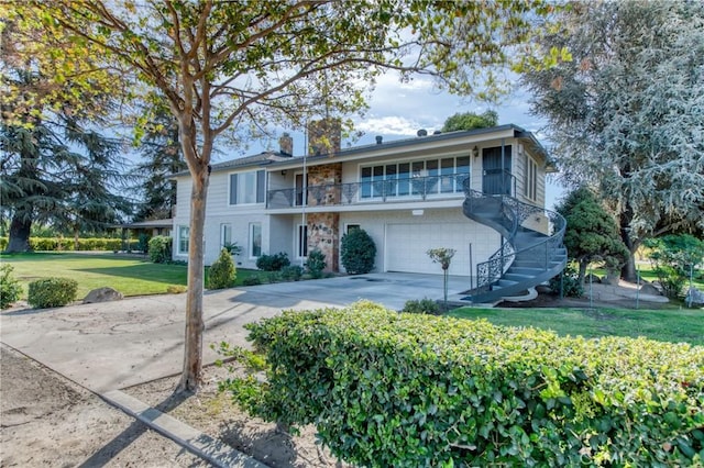 view of front of house featuring a balcony, a front yard, concrete driveway, an attached garage, and a chimney