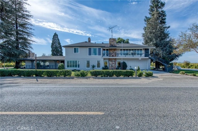 view of front of house with an attached garage, a balcony, a chimney, and driveway