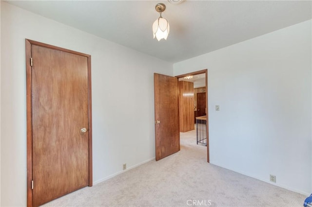 unfurnished bedroom featuring light colored carpet, a closet, and baseboards