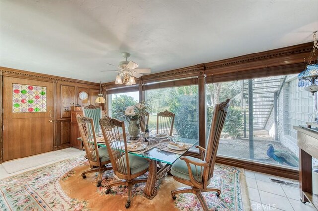 dining area with ceiling fan, light tile patterned floors, and wood walls