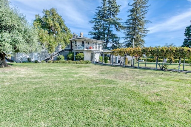 view of grassy yard with a balcony
