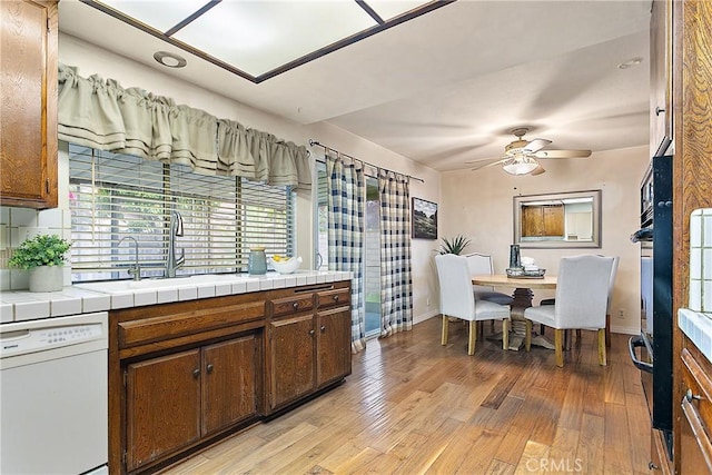 20672 Chaucer Ln, Huntington Beach, CA 92646 - kitchen with white dishwasher, a sink, tile counters, ceiling fan, and light wood-style flooring