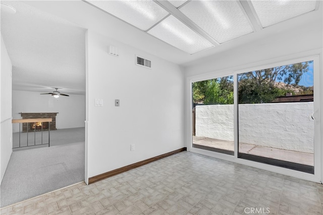 empty room featuring tile patterned floors, ceiling fan, a warm lit fireplace, and baseboards