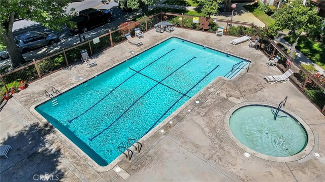 community pool with a patio area and fence