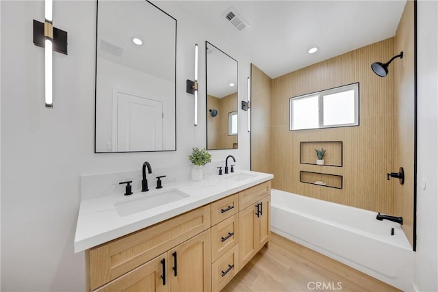full bath featuring double vanity, tub / shower combination, and wood finished floors