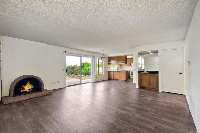 3579 Twilight Ln, Oceanside, CA 92056 - unfurnished living room with a fireplace, dark wood-style flooring, a textured ceiling, a chandelier, and a sink