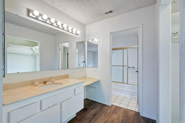 3579 Twilight Ln, Oceanside, CA 92056 - bathroom with vanity, wood finished floors, shower / bath combination with glass door, and a textured ceiling