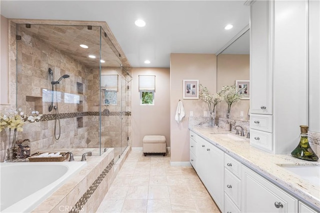 bathroom featuring a shower stall, a bath, double vanity, recessed lighting, and baseboards