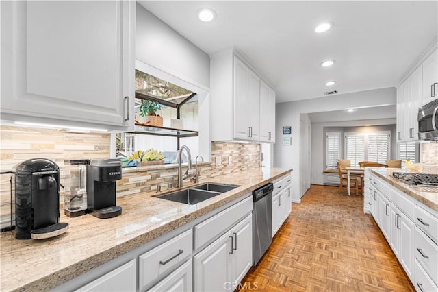 kitchen featuring a sink, appliances with stainless steel finishes, healthy amount of natural light, white cabinets, and recessed lighting
