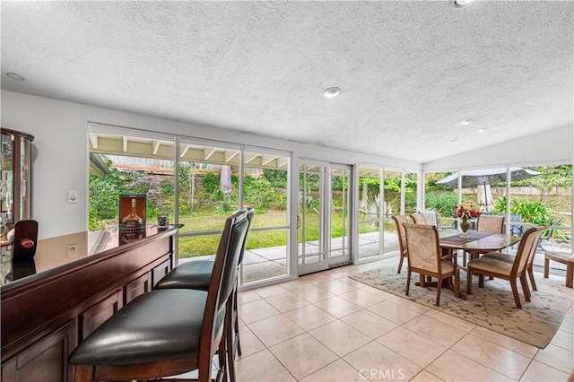 sunroom / solarium featuring french doors, a textured ceiling, healthy amount of natural light, tile patterned flooring, and vaulted ceiling