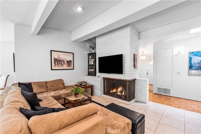 living area with a brick fireplace, beam ceiling, and a textured ceiling