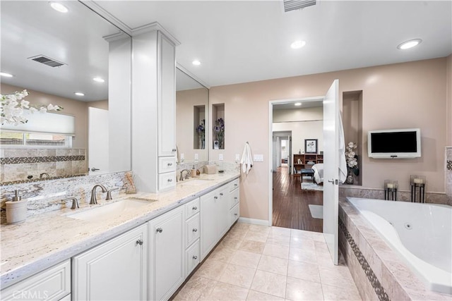 bathroom featuring a jetted tub, double vanity, baseboards, tile patterned flooring, and recessed lighting
