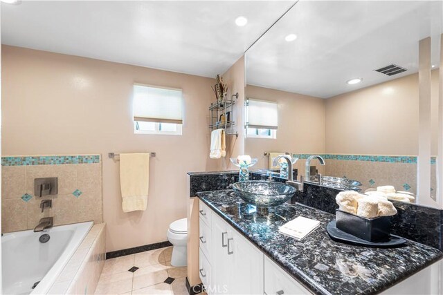 bathroom featuring tile patterned floors, vanity, a garden tub, toilet, and baseboards