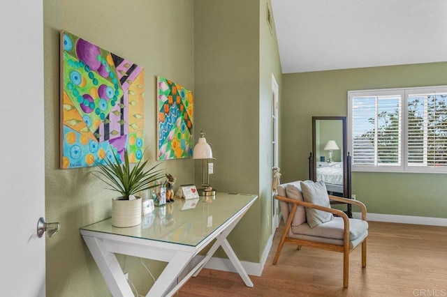 sitting room featuring wood finished floors, baseboards, and lofted ceiling