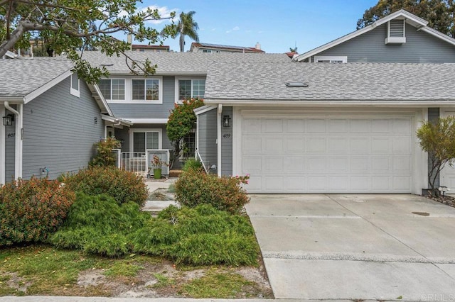 view of front facade with an attached garage, concrete driveway, and a shingled roof