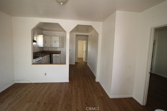 404 N 4th Ave, Barstow, CA 92311 - kitchen with dark wood-type flooring, white cabinets, baseboards, a sink, and dark countertops