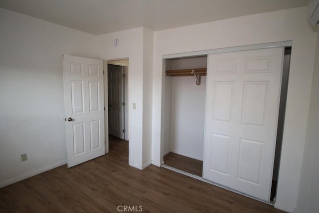 404 N 4th Ave, Barstow, CA 92311 - unfurnished bedroom with wood finished floors, baseboards, a wall mounted AC, and a closet