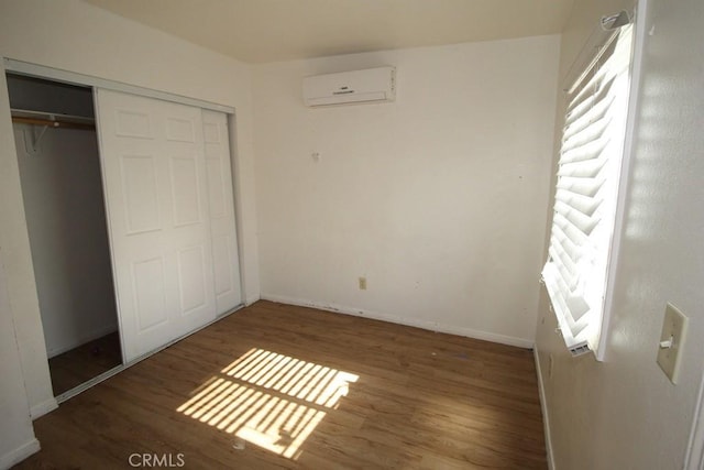 404 N 4th Ave, Barstow, CA 92311 - unfurnished bedroom with an AC wall unit, wood finished floors, a closet, and baseboards