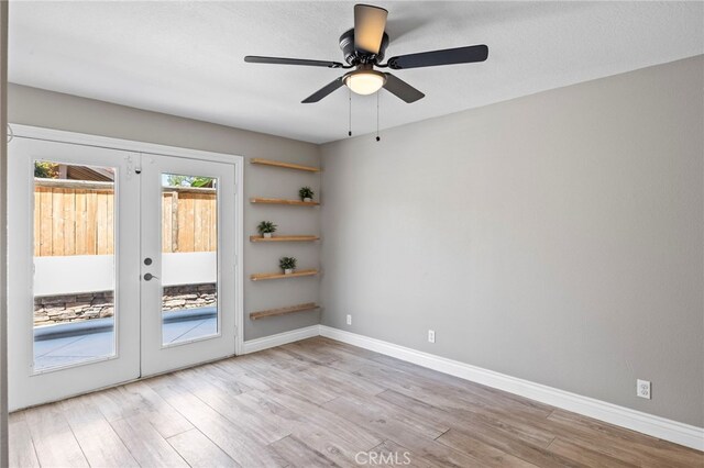 unfurnished room with french doors, light wood-style flooring, ceiling fan, and baseboards