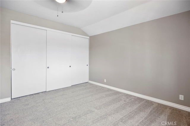 unfurnished bedroom with carpet flooring, lofted ceiling, baseboards, and a closet