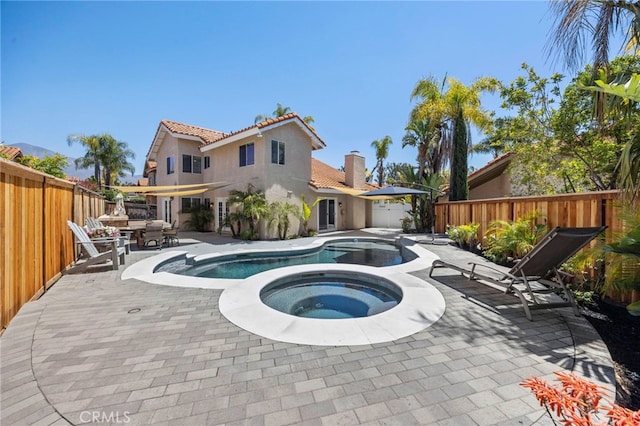 view of swimming pool with an in-ground hot tub, a patio, and a fenced backyard