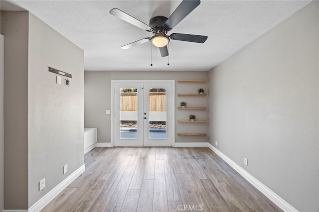 spare room with french doors, wood finished floors, ceiling fan, baseboards, and a textured ceiling