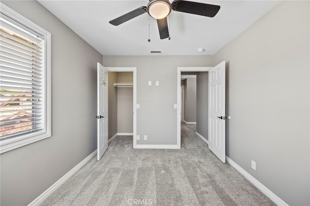 unfurnished bedroom with carpet, multiple windows, baseboards, and a spacious closet