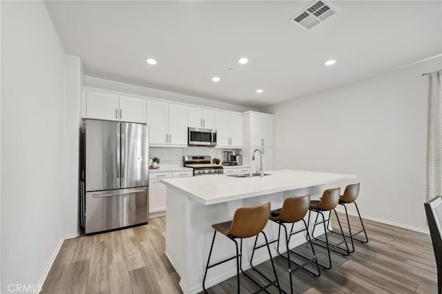 148 Camden Ct, Perris, CA 92571 - kitchen featuring appliances with stainless steel finishes, a sink, light wood-type flooring, a kitchen breakfast bar, and recessed lighting
