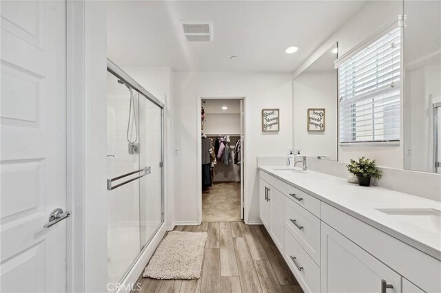 148 Camden Ct, Perris, CA 92571 - full bathroom featuring a stall shower, wood finished floors, double vanity, a spacious closet, and recessed lighting