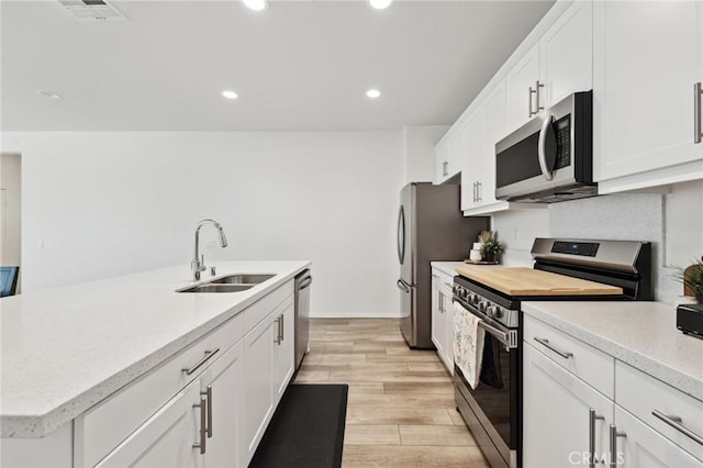 148 Camden Ct, Perris, CA 92571 - kitchen featuring stainless steel appliances, a sink, white cabinetry, recessed lighting, and light wood-style flooring