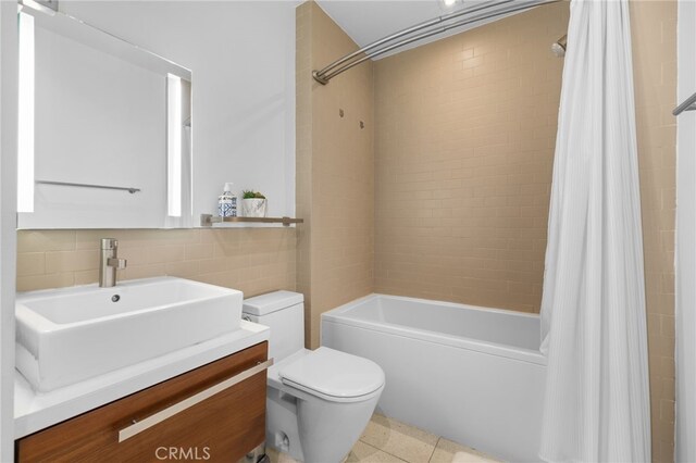 full bath featuring toilet, shower / bath combination with curtain, vanity, and tile walls