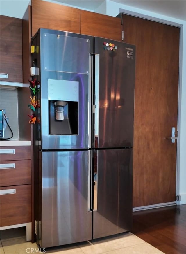 kitchen with stainless steel refrigerator with ice dispenser, light wood-style floors, modern cabinets, and light countertops