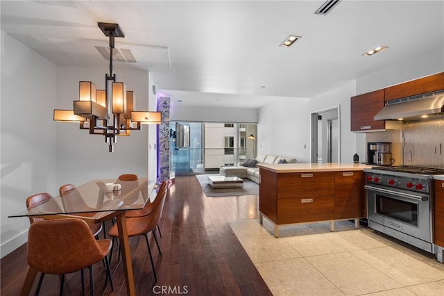 kitchen featuring luxury range, under cabinet range hood, a chandelier, a peninsula, and modern cabinets