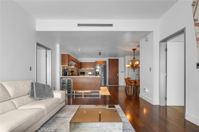 living room featuring dark wood-style flooring, a chandelier, wine cooler, and baseboards