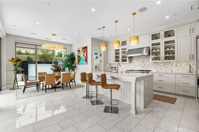 244 Coal Mine, Irvine, CA 92602 - kitchen featuring exhaust hood, light countertops, light marble finish flooring, decorative backsplash, and a center island with sink