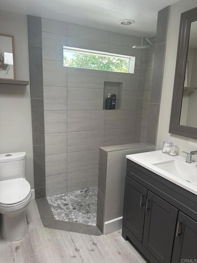 full bath featuring toilet, a walk in shower, wood finished floors, and vanity