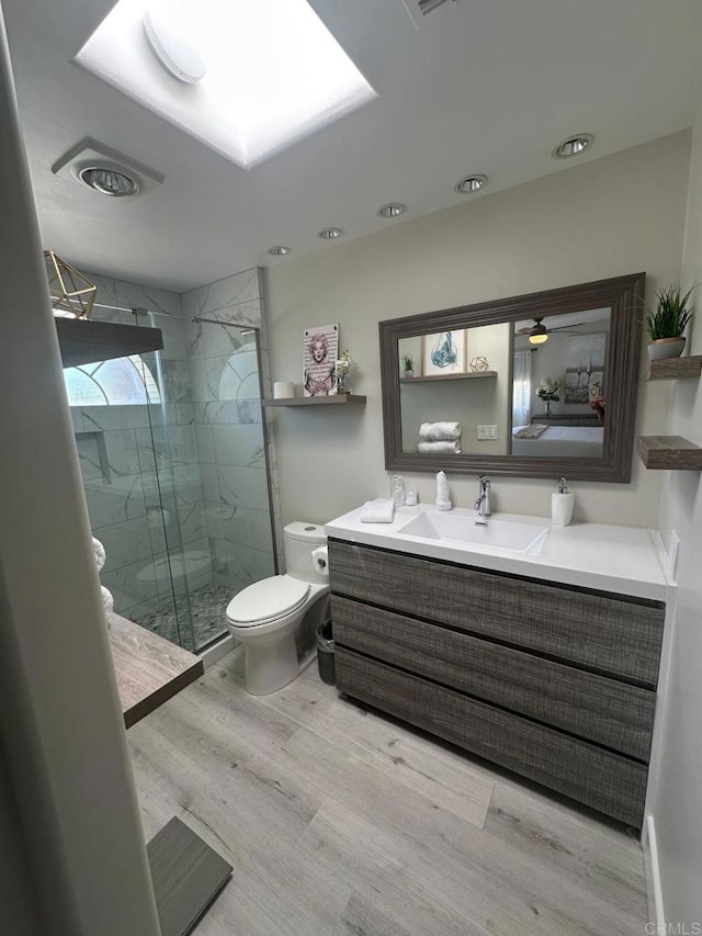 full bath featuring toilet, a marble finish shower, wood finished floors, and vanity