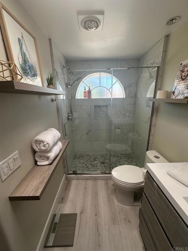 full bathroom with wood finished floors, toilet, a shower stall, and vanity