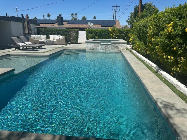 view of swimming pool featuring a pool with connected hot tub, a patio, and an outdoor hangout area